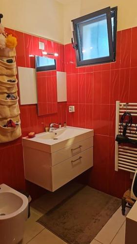 La salle de bains rouge est pourvue d'un lavabo et de toilettes. dans l'établissement Petit Paradis à Bandol t4 piscine clim Parking Fibre Coffre-fort, à Bandol
