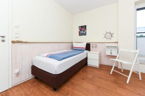 a bedroom with a bed and a desk and a chair at Ferienwohnungen MARENOR in Bensersiel