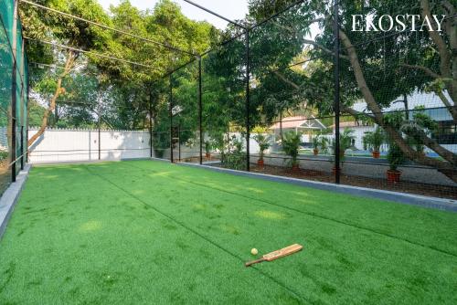 a tennis court with a bat and a ball on it at EKOSTAY - White Oak Villa in Alibaug
