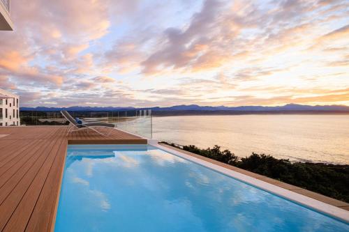 a swimming pool on a deck with a view of the water at The Plettenberg Hotel in Plettenberg Bay