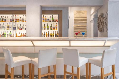 a bar with four white chairs and a counter at The Plettenberg Hotel in Plettenberg Bay
