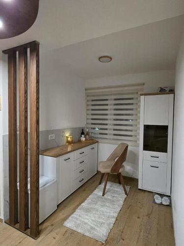 a kitchen with white cabinets and a chair in it at Hotel Mažijanik in Nikšić