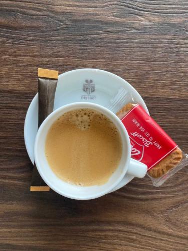 a cup of coffee on a plate with a piece of bread at DRIEHOF LifeStyle Suite Apt 1 in Tecklenburg