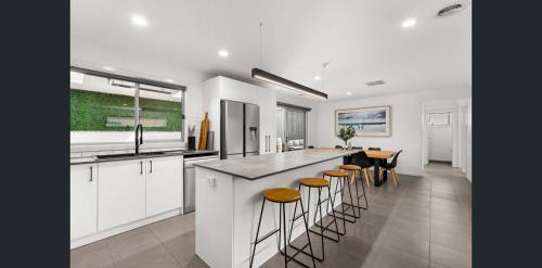 a kitchen with white cabinets and a bar with stools at City and Sea Retreat - Family Friendly Stay in Marshalltown