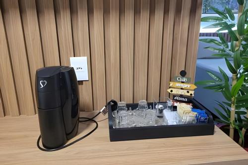 a black router sitting on a table with glasses at Vida Urbana - Allegro - Setor Oeste in Goiânia