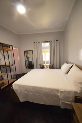 a bedroom with a large white bed and a table at Mami Affittacamere in Genova