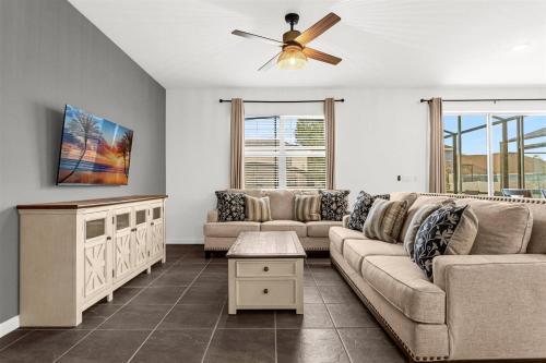a living room with a couch and a ceiling fan at Upstay Ultimate Orlando Retreat w Pool & Hot Tub Sleeps 16 in Kissimmee