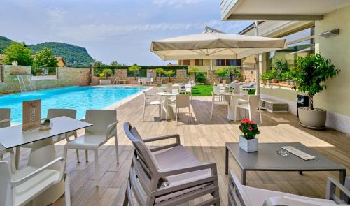 a patio with tables and chairs and a swimming pool at Hotel Eden Garda in Garda