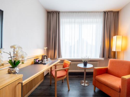 a hotel room with a desk and chairs at Best Western Hotel Heidehof in Hermannsburg