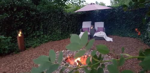 a fire pit with two chairs and an umbrella at Gästehaus am Kattensteert in Borchel