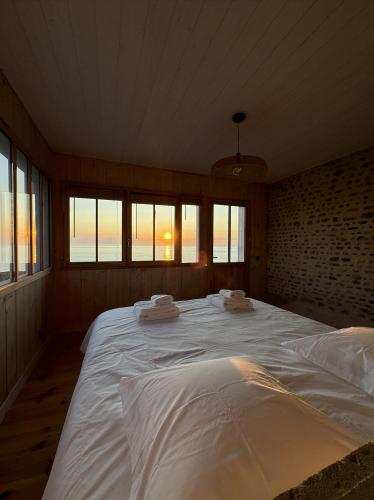 un grand lit blanc dans une pièce avec des fenêtres dans l'établissement Villa Bord de Mer, Vue Océan et Accés Plage, à Soulac-sur-Mer