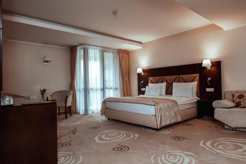 a bedroom with a bed and a chair and a couch at Grand Hotel Coroana in Bistriţa