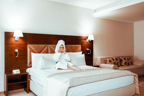 a woman sitting on a bed talking on a cell phone at Grand Hotel Coroana in Bistriţa