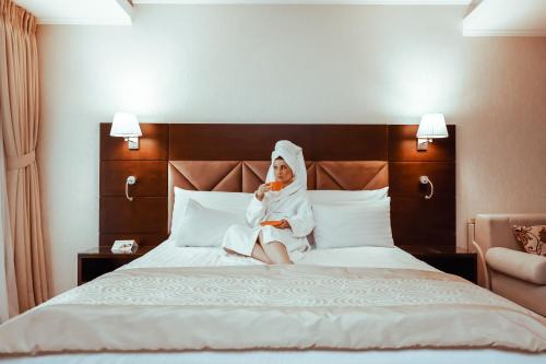 a woman sitting on a bed in a hotel room at Grand Hotel Coroana in Bistriţa