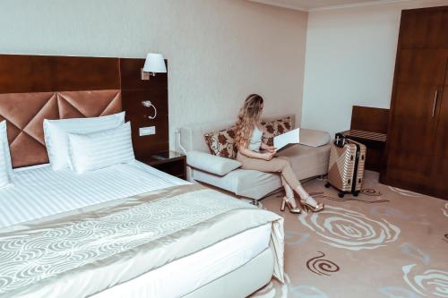 a woman sitting on a couch in a hotel room at Grand Hotel Coroana in Bistriţa