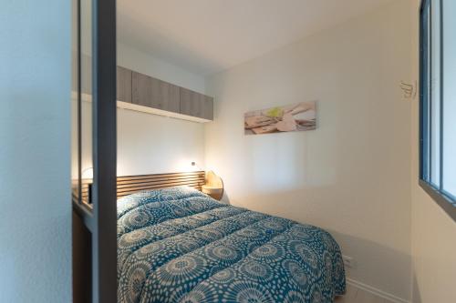 une chambre avec un lit avec une couverture bleue dans l'établissement Cosy Gallieni - Bel appt avec terrasse à Merignac, à Mérignac