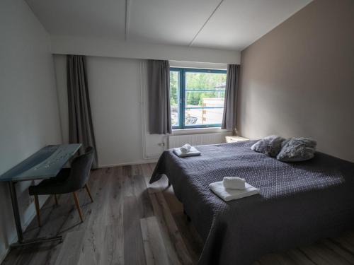 a bedroom with a bed and a desk and a window at Polku Hotelli in Vihti