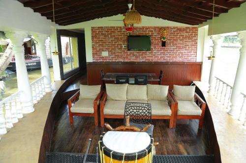 a room with chairs and a table and a television at Marari houseboat in Mararikulam