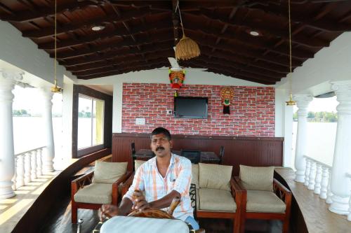 a man sitting in a chair in a restaurant at Marari houseboat in Mararikulam