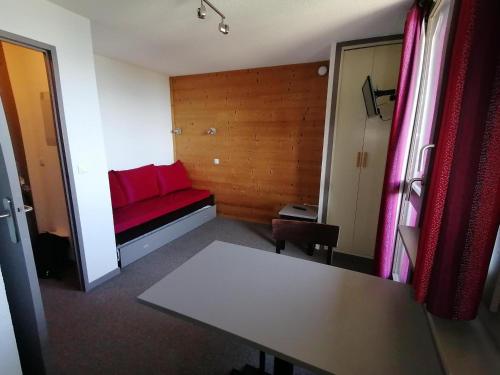 une chambre avec un canapé rouge et une table dans l'établissement Studio rénové au pied des pistes - FR-1-181-2472, à Aime La Plagne
