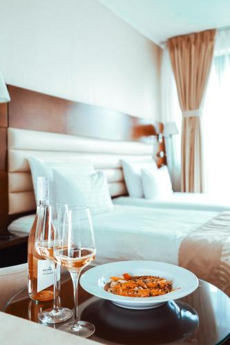 a table with a plate of food and two glasses of wine at Grand Hotel Coroana in Bistriţa