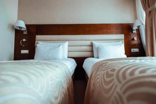 two beds sitting next to each other in a room at Grand Hotel Coroana in Bistriţa