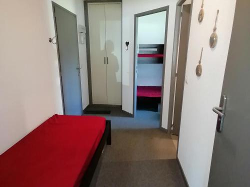 Cette chambre comprend un lit rouge et un couloir. dans l'établissement Appartement Rénové, Accès Direct aux Pistes, Balcon, Parking Gratuit, 5 Pers. - FR-1-181-2473, à Aime La Plagne