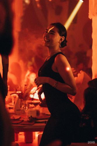a woman in a black dress dancing in a room at Отель у Ботанического Сада, в самом центре in Astana