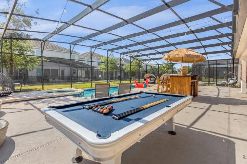 a pool table in a patio with a swimming pool at Upstay Family Resort Mansion- Pool, Games, Theater in Kissimmee