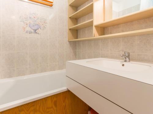 La salle de bains blanche est pourvue d'un lavabo et d'une baignoire. dans l'établissement Studio fonctionnel au centre station avec balcon et vue montagne, 2 étoiles - FR-1-181-2494, à La Plagne Tarentaise