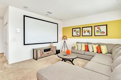 a living room with a couch and a large screen at Family Resort - 6BR Mansion - Private Pool, Home Theater, BBQ and More in Kissimmee