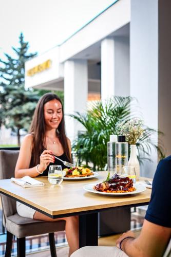 a woman sitting at a table with a plate of food at Grand Hotel Coroana in Bistriţa