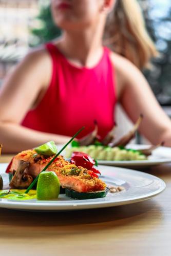a woman sitting at a table with a plate of food at Grand Hotel Coroana in Bistriţa