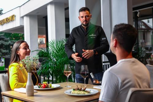 a man standing in front of a table with a group of people at Grand Hotel Coroana in Bistriţa
