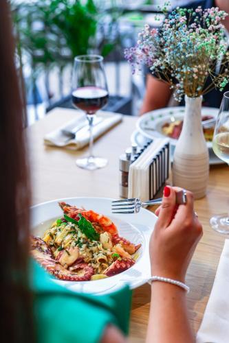 a woman sitting at a table with a plate of food at Grand Hotel Coroana in Bistriţa