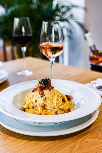 a plate of pasta on a table with a glass of wine at Grand Hotel Coroana in Bistriţa