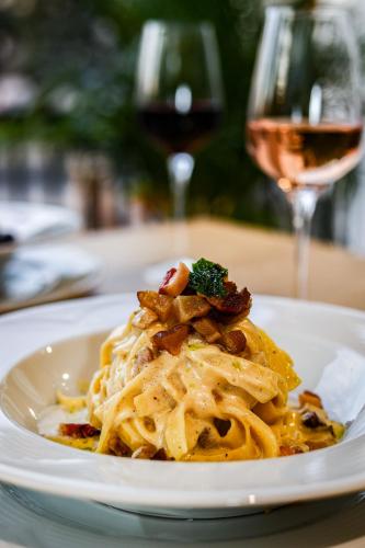 a plate of pasta on a table with a glass of wine at Grand Hotel Coroana in Bistriţa