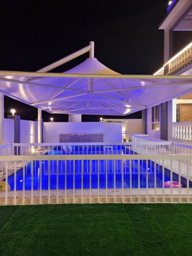 a white pavilion with a pool at night at سمارت شاليه: Smart Chalet in Salalah