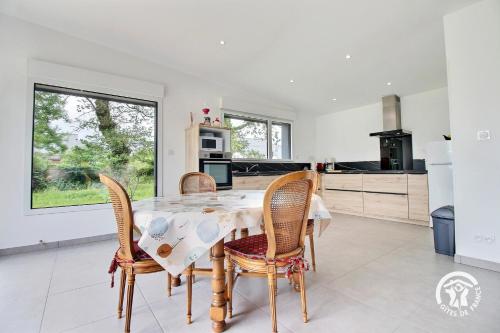 une salle à manger avec une table et des chaises dans une cuisine dans l'établissement Merlin du Val, à Campénéac