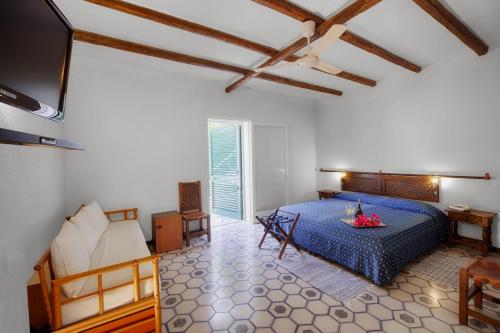 1 dormitorio con 1 cama azul y TV en Hotel Conti, en Vulcano