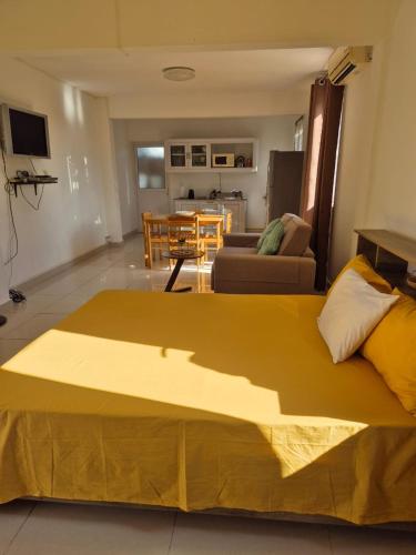 a large yellow bed in a living room with a table at Riverside Studio in La Gaulette