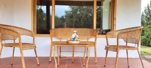 two wicker chairs and a table on a porch at Casa Ecológica Al Pie Del Volcán in Otavalo