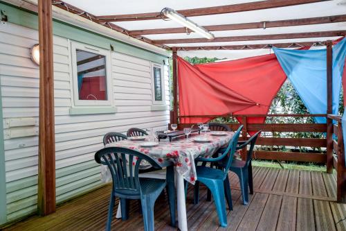 - une table et des chaises sur la terrasse d'une maison dans l'établissement Mobil-home climatisé, camping 3étoiles, 5 min du Lac et à 15 min de Mimizan-Plage, à Sainte-Eulalie-en-Born