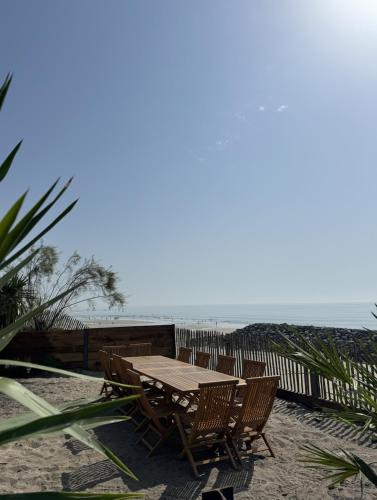- une table et des chaises en bois sur la plage dans l'établissement Villa Bord de Mer, Vue Océan et Accés Plage, à Soulac-sur-Mer