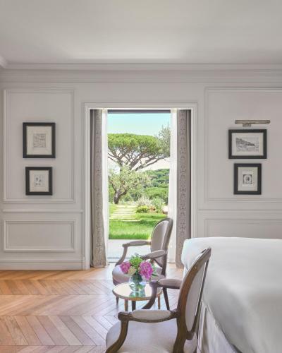 a bedroom with a bed and two chairs and a window at Airelles Château de la Messardière in Saint-Tropez
