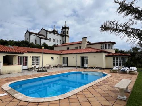 a villa with a swimming pool in front of a house at Casa da Fazenda in Santa Cruz das Flores