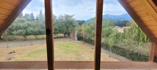 an open window with a view of a field at Casa Ecológica Al Pie Del Volcán in Otavalo
