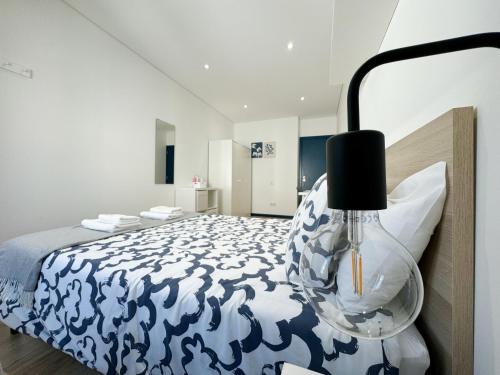 een slaapkamer met een blauw en wit bed en een lamp bij Guest House DML in Aveiro
