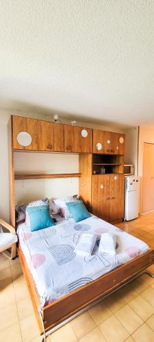 een groot bed met een houten hoofdeinde in een kamer bij EDEN studio - Gréoux-Les-Bains in Gréoux-les-Bains