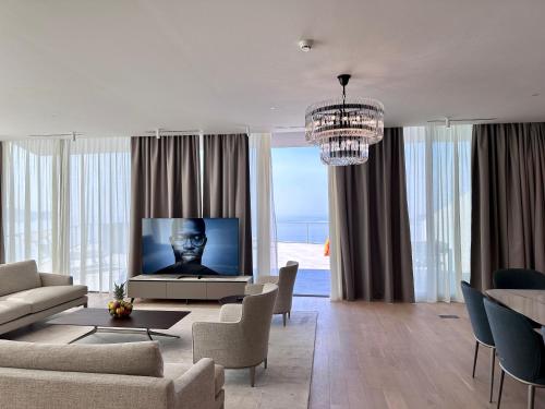 a living room with a television and a couch and chairs at Sea Star Budva in Budva